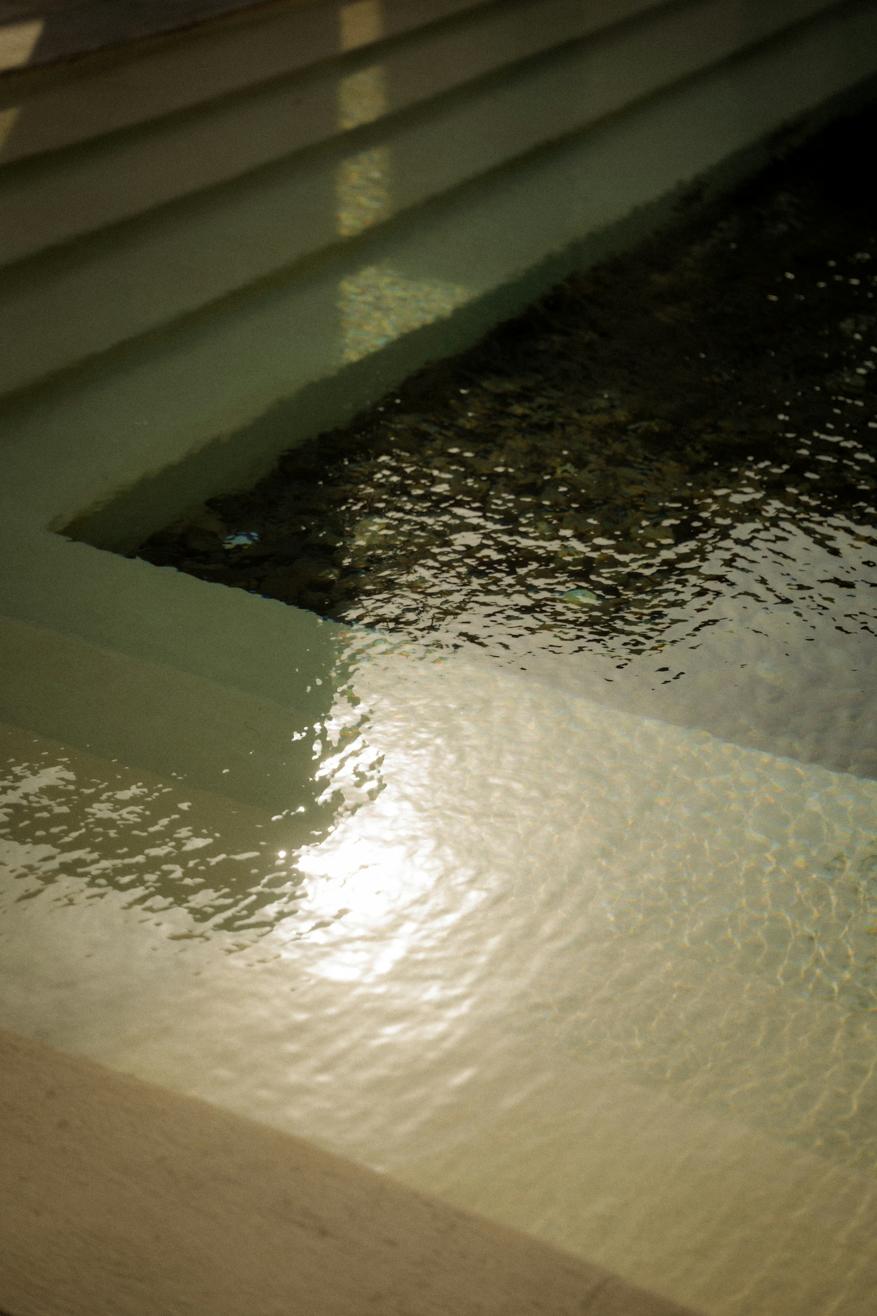 Clear coastal water meeting pale stone in warm light.